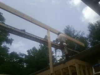Carpenter setting a ridge beam over a new addition frame — Ice Dam Removal by Roofing Brothers in Big Rapids