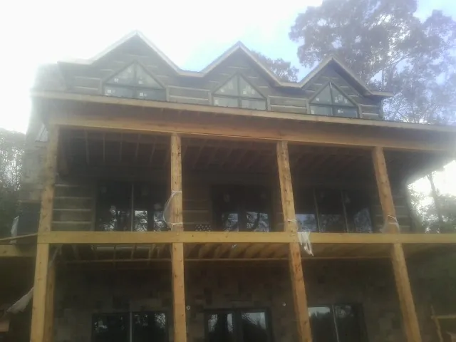 Dormers and porch framing on a large log home under construction — Roof Coating work by our crew in Big Rapids