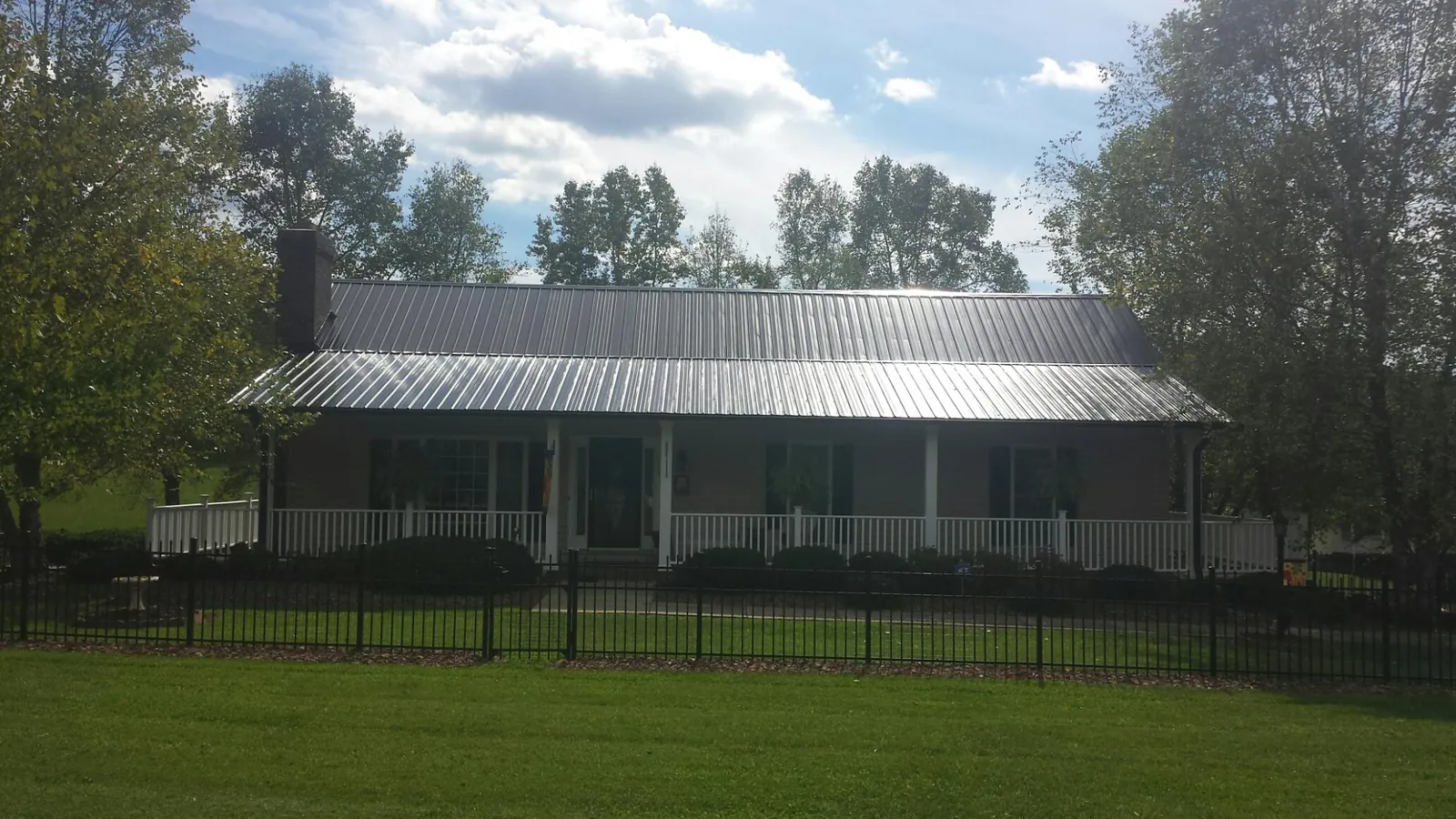 Gray metal roof on a brick ranch with a full width front porch — Gutter Guard Installation work by our crew in Big Rapids