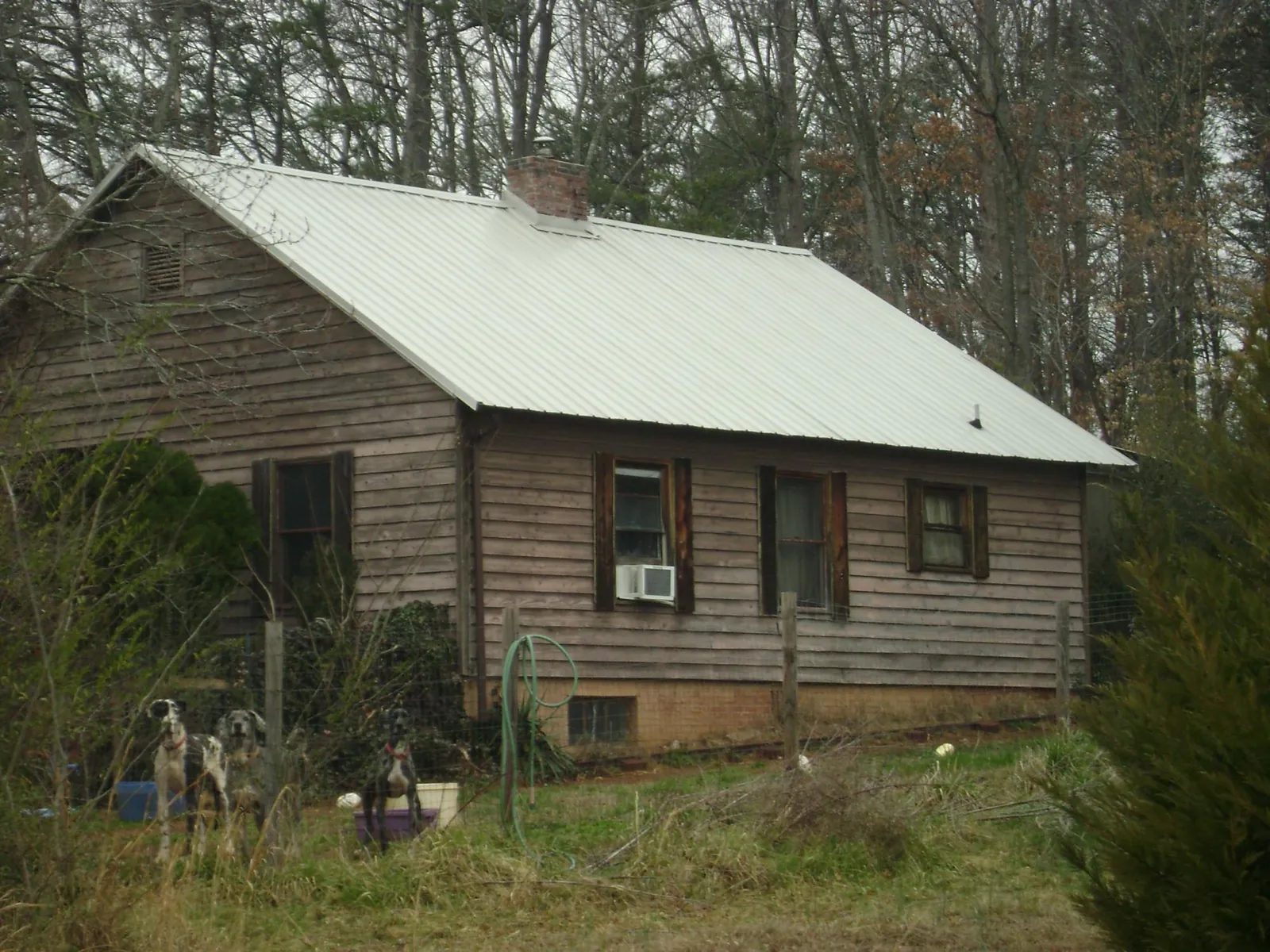 White metal roof on an old wood sided farmhouse, from a Metal Roof Installation job in Big Rapids