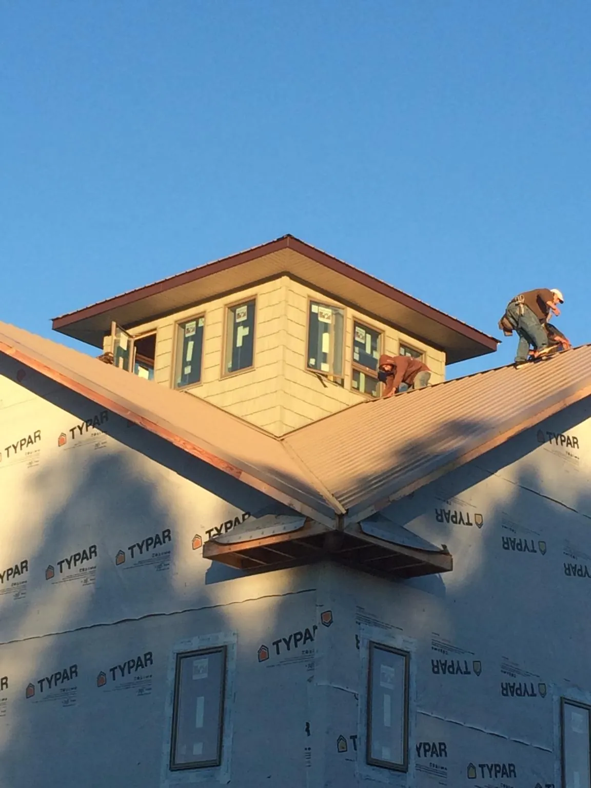 Roofers working around a rooftop cupola on a new metal roof at sunset — Roof Waterproofing in Big Rapids by Roofing Brothers